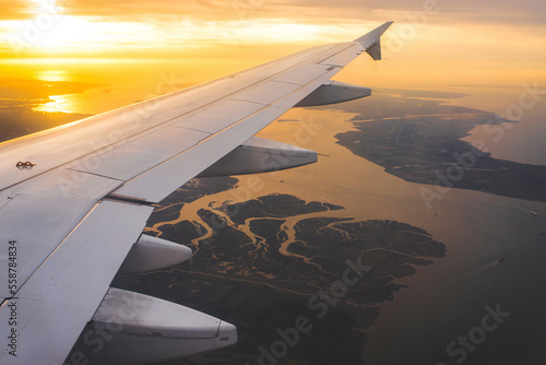 Cropped image of airplane flying over seascape against cloudy sky during sunset