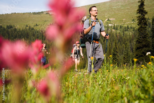 Selective focus, low angle view of a group of hikers in the Purcell Mountains, seen through red Indian Paintbrush wildflowers. photo