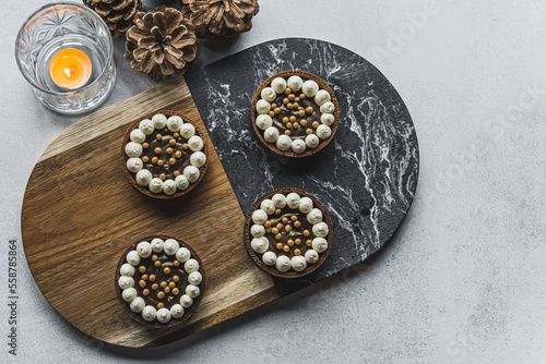 Top view of four beautiful small chocolate tarts decorated with small meringues and pearls. Artistic bakery goods. High quality photo