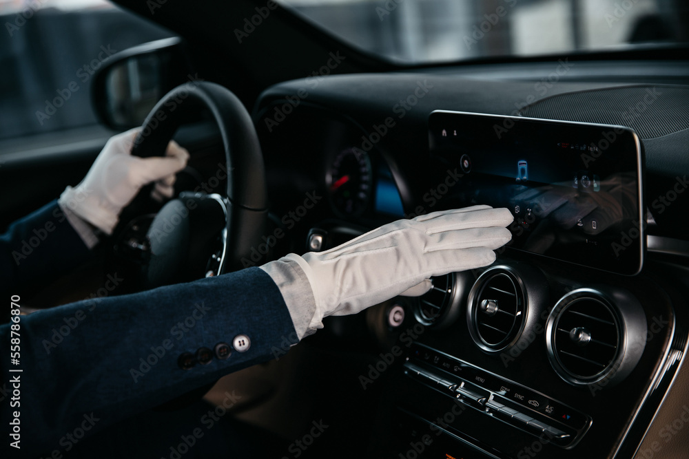 manager in a white glove demonstrates the functions of a luxury car