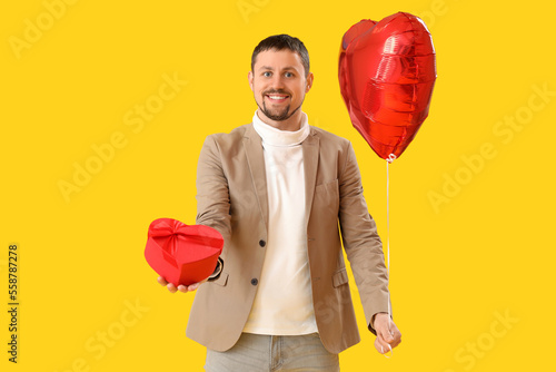 Smiling man holding red hea...