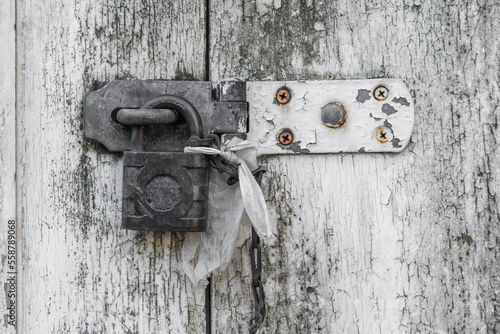 Heavy duty old hasp and padlock against a white weathered wooden door.