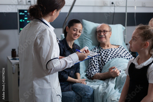 Foto Elderly people care nurse reviewing files of senior male patient bedridden in geriatric hospital