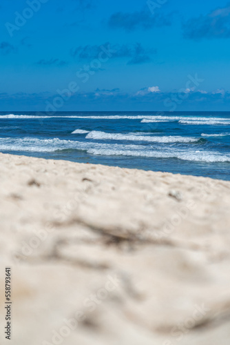 Wei  er tropischer Sandstrand mit strahlend blauen Meer und einer Felsen im Hintergrund  Indonesien  Bali