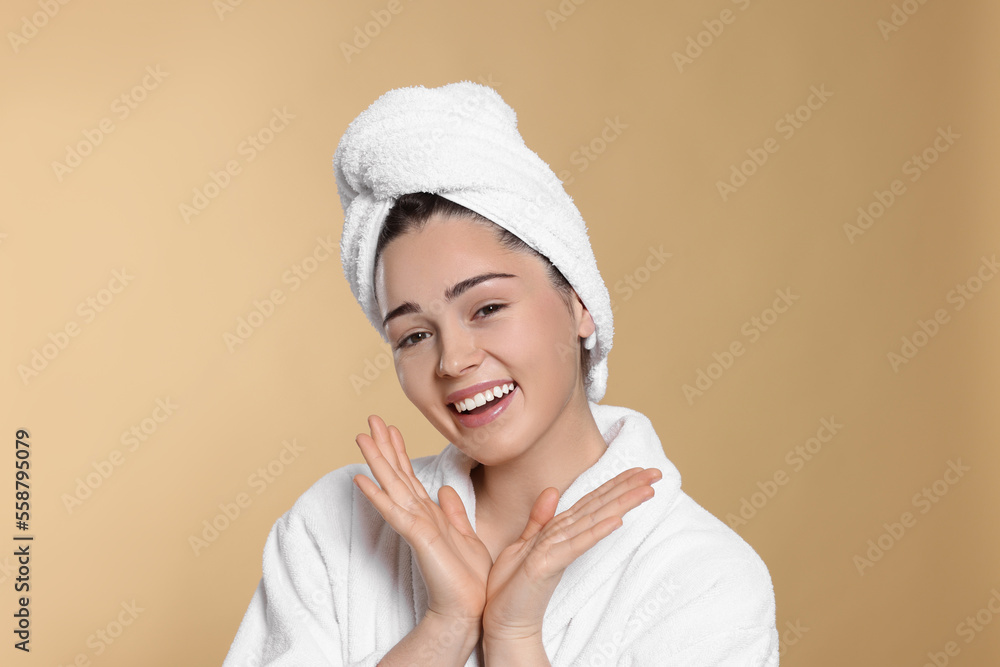 Portrait of attractive young woman in bathrobe with towel on beige background. Spa treatment Portrait of attractive young woman in bathrobe with towel on beige background. Spa treatment