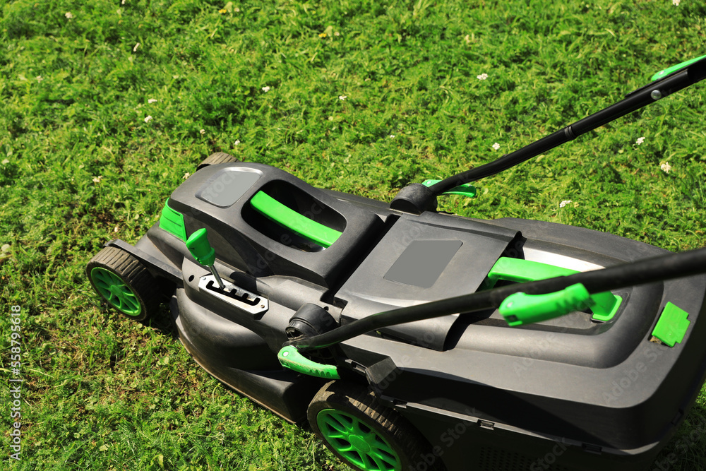Lawn mower on green grass in garden Lawn mower on green grass in garden