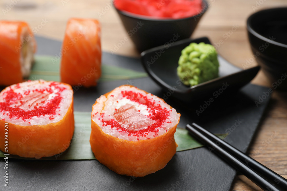 Delicious sushi rolls with tobiko on wooden table, closeup