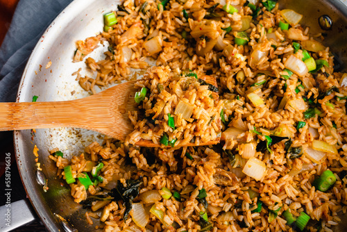 Kimchi Fried Rice Scooped on a Bamboo Spatula: Closeup of kimchi bokkeumbap on a wood spatula above a skillet photo