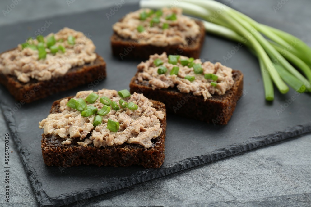 Tasty sandwiches with cod liver and green onion on light grey table Tasty sandwiches with cod liver and green onion on light grey table