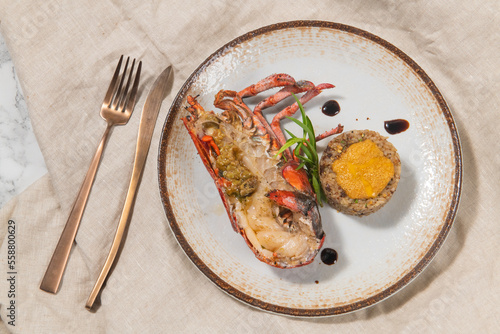 Lobster with risotto on a white plate with fork and knife.
