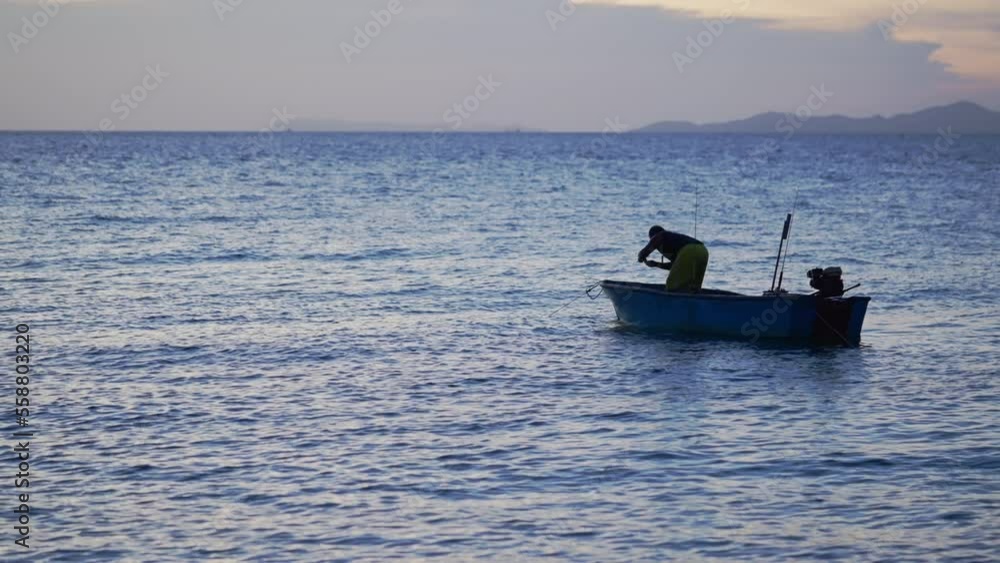 Man fishing on sea water in a boat at sunset, Fisherman try to catch fish with rods and reel on a ship in twilight, Silhouette of anglers fishing ocean on boat at evening, Slow motion, Handhel view. Man fishing on sea water in a boat at sunset, Fisherman try to catch fish with rods and reel on a ship in twilight, Silhouette of anglers fishing ocean on boat at evening, Slow motion, Handhel view.
