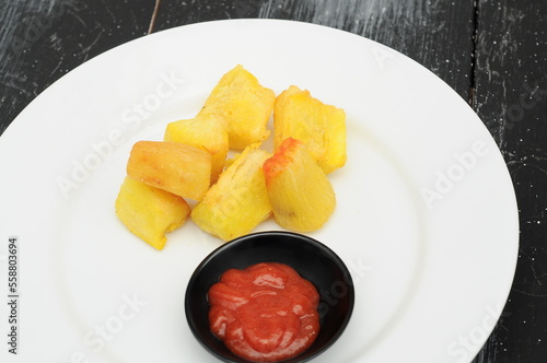 fried sweet potatoes on a white plate and a black wooden table