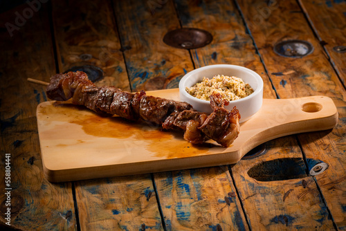 Espetinho de churrasco com farofa em tábua de madeira