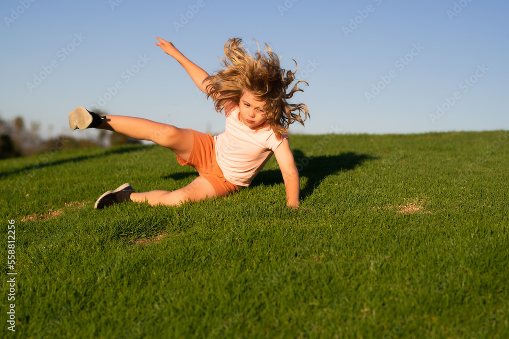 Kid runs through the spring grass and falling down on the ground in park.  Moment of