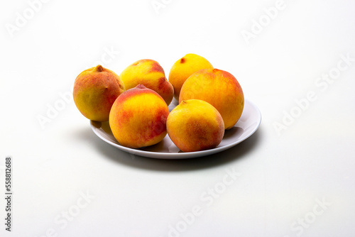 ripe peaches in a shallow dish, on a white milky background.