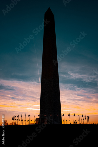 The Washington Monument is a 555-foot tall obelisk located in Washington, D.C. Picture of backlit of obelisk in sunset with few clouds.