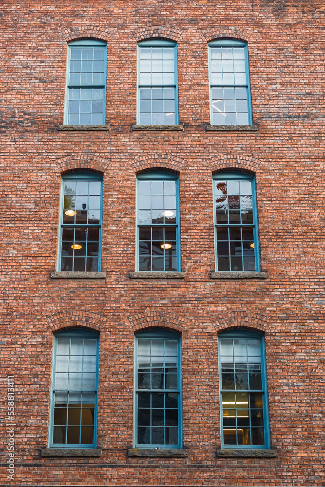 Many equal windows of the factory. Old red brick building or factory with many windows