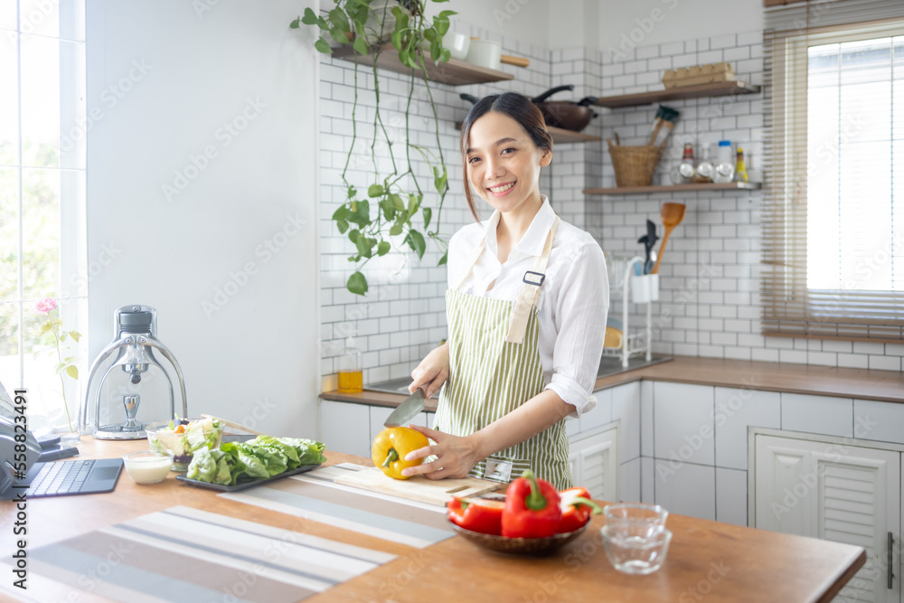 Portrait of attractive asian japanese woman in kitchen at home, young girl browsing website on tutor cooking class and doing for kitchen, cutting vegetables, cooking, cooking concept. Portrait of attractive asian japanese woman in kitchen at home, young girl browsing website on tutor cooking class and doing for kitchen, cutting vegetables, cooking, cooking concept.