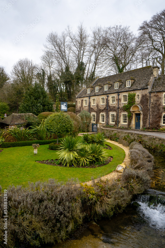 Classic Swan hotel in Bibury , classic villages in Cotwolds stone buildings and river coln during winter cloudy day at Gloucestershire , United Kingdom : 6 March 2018 Classic Swan hotel in Bibury , classic villages in Cotwolds stone buildings and river coln during winter cloudy day at Gloucestershire , United Kingdom : 6 March 2018