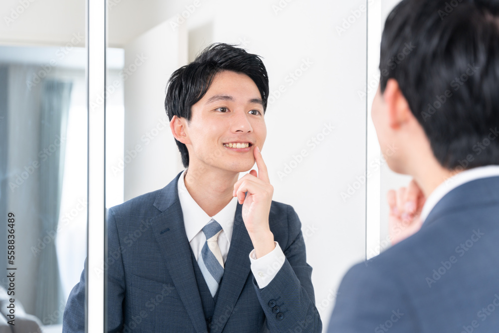 鏡を見て歯のチェックをするビジネスマン（ホワイトニング・歯並び・歯列矯正）