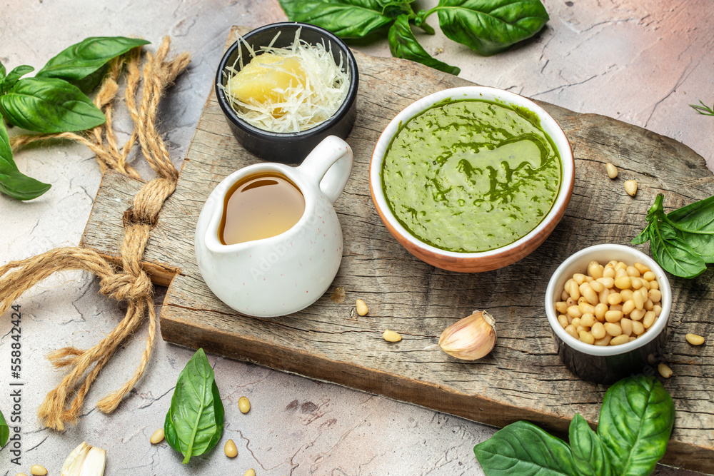 Green basil pesto with italian recipe ingredients, Basil, olive oil, parmesan, garlic, pine nuts. banner, menu, recipe place for text, top view Green basil pesto with italian recipe ingredients, Basil, olive oil, parmesan, garlic, pine nuts. banner, menu, recipe place for text, top view