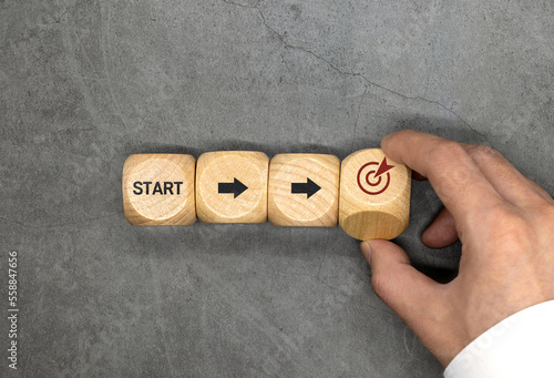 Starting point and a wooden cube with an arrow pointing to the target icon. Growing business success concept