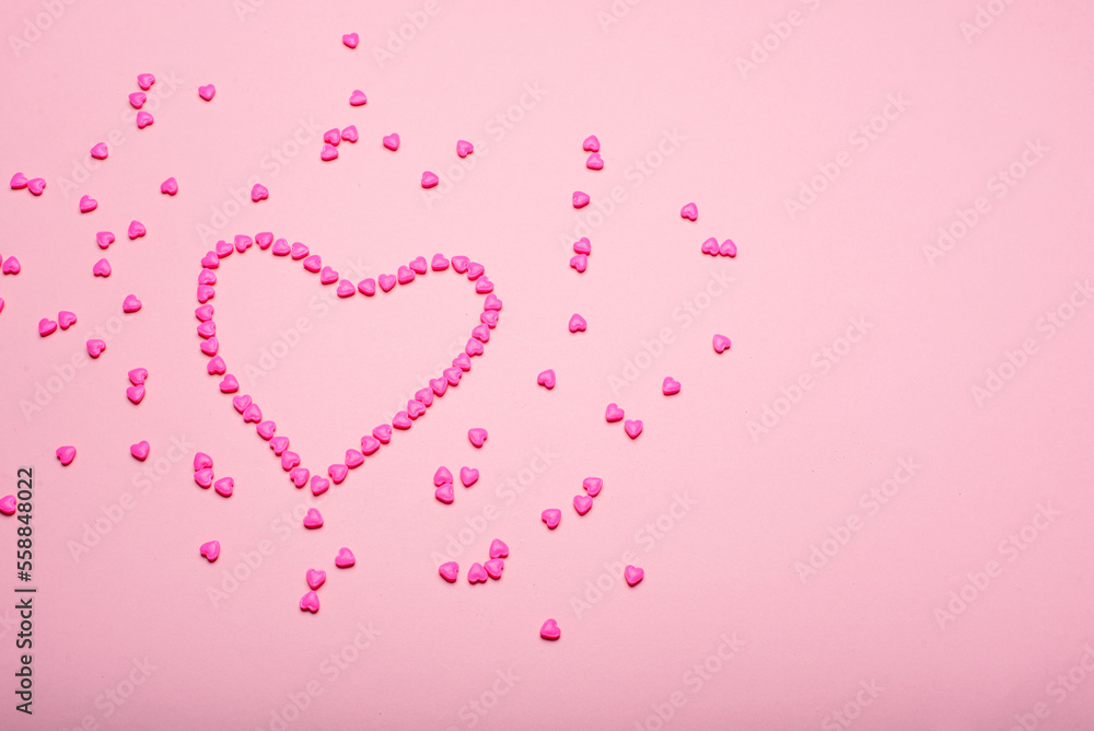 Heart-shaped frame made with small hearts on a pink background.