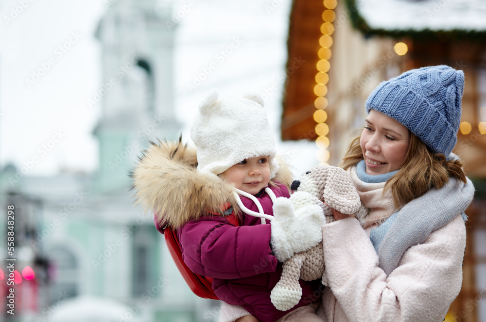 Mother and daughter are walking around the city on Christmas and New Year holidays. Parent and little child having fun outdoors Mother and daughter are walking around the city on Christmas and New Year holidays. Parent and little child having fun outdoors