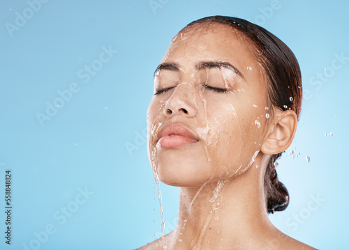 Woman, face skincare or water splash on blue background studio for healthcare wellness, Brazil hygiene maintenance or self care grooming. Beauty model, showering or wet water drop for facial cleaning photo