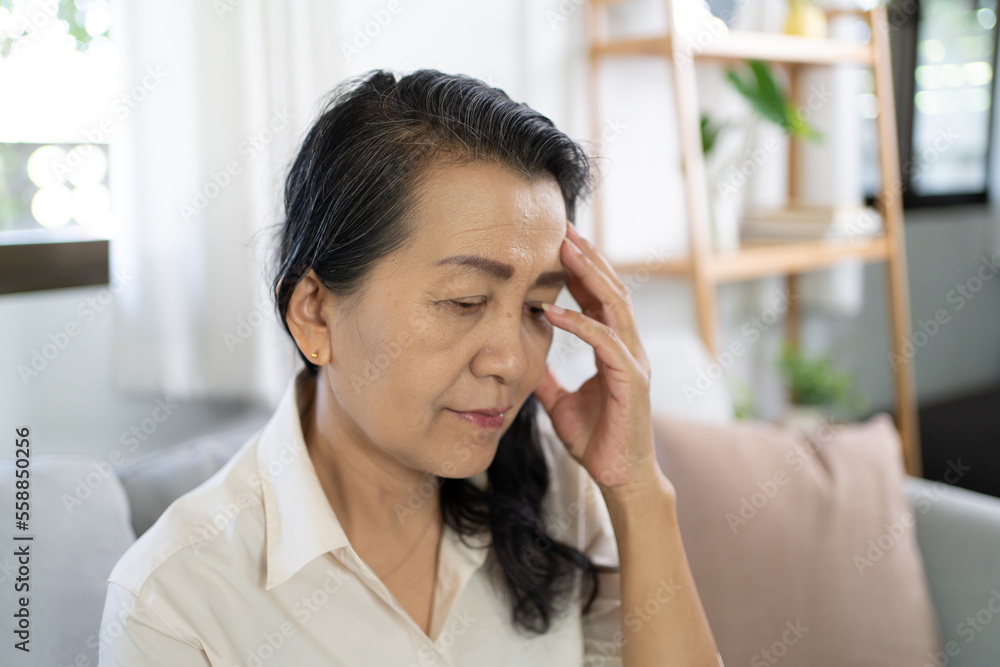 Middle age Asian woman touching forehead having headache suffering from. migraine feeling sick or depression Middle age Asian woman touching forehead having headache suffering from. migraine feeling sick or depression