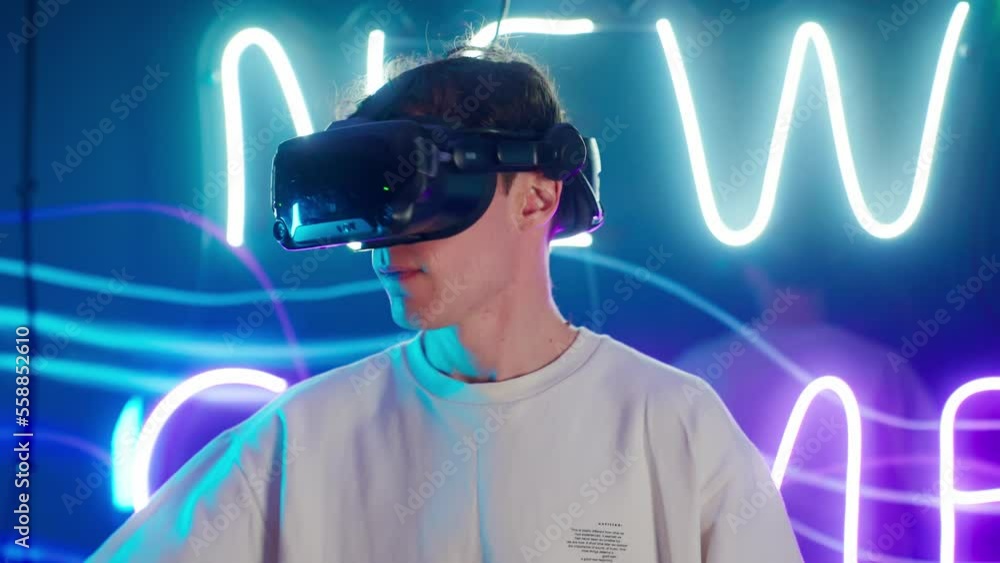 Cyber gamer in VR glasses plays virtual reality game in neon futuristic space. Cyberpunk fashion gaming concept. Man and woman play metaverse virtual digital technology game control with VR goggle. Cyber gamer in VR glasses plays virtual reality game in neon futuristic space. Cyberpunk fashion gaming concept. Man and woman play metaverse virtual digital technology game control with VR goggle.