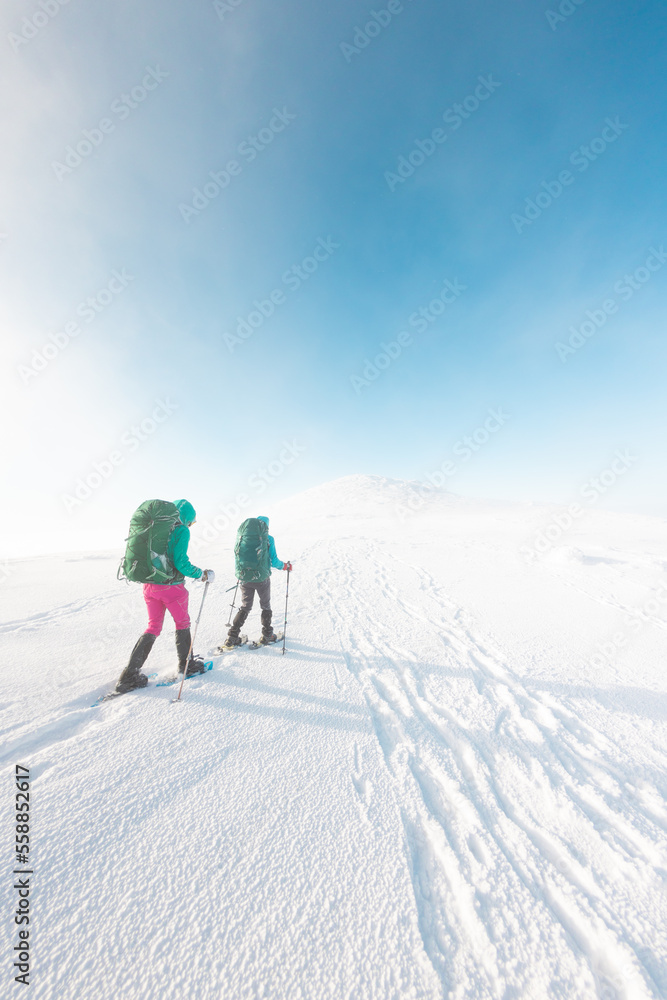 two tourists in winter mountains on snowshoes