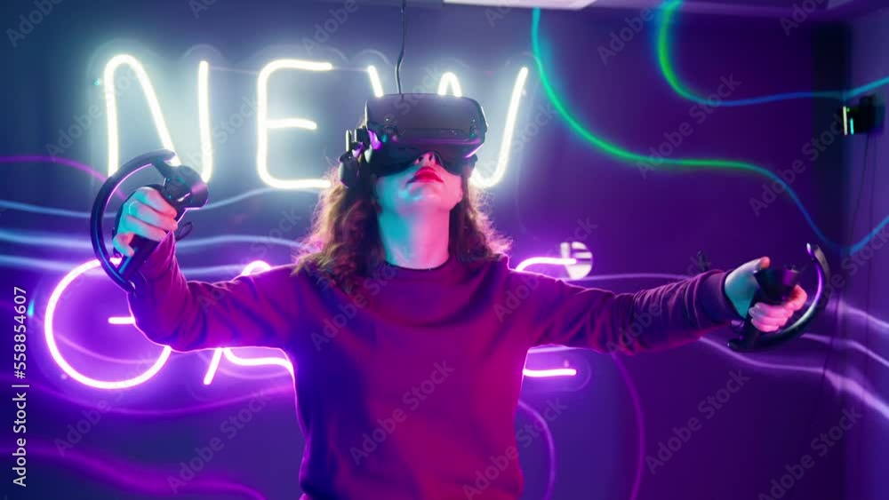 Cyber gamer in VR glasses plays virtual reality game in neon futuristic space. Cyberpunk fashion gaming concept. Man and woman play metaverse virtual digital technology game control with VR goggle. Cyber gamer in VR glasses plays virtual reality game in neon futuristic space. Cyberpunk fashion gaming concept. Man and woman play metaverse virtual digital technology game control with VR goggle.