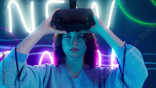 Cyber gamer in VR glasses plays virtual reality game in neon futuristic space. Cyberpunk fashion gaming concept. Man and woman play metaverse virtual digital technology game control with VR goggle.