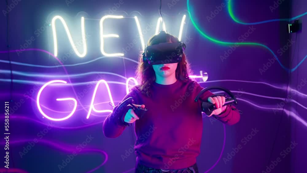 Cyber gamer in VR glasses plays virtual reality game in neon futuristic space. Cyberpunk fashion gaming concept. Man and woman play metaverse virtual digital technology game control with VR goggle. Cyber gamer in VR glasses plays virtual reality game in neon futuristic space. Cyberpunk fashion gaming concept. Man and woman play metaverse virtual digital technology game control with VR goggle.