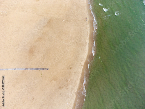 aerial view of beach landscape with loungers and pink umbrellas close to sea.