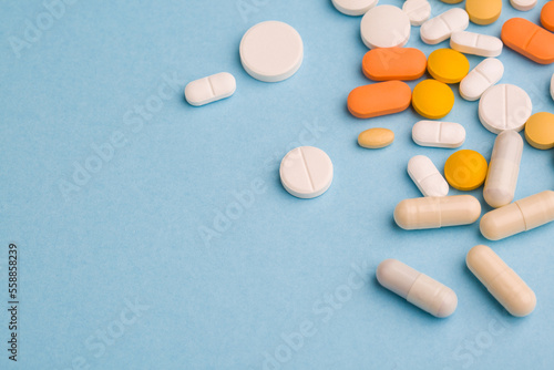 Assorted pharmaceutical medicine pills, tablets and capsules on blue background. Copy space for text