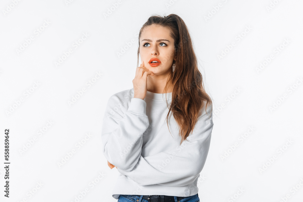 Thoughtful troubled young woman touch chin, thinking. Girl searching solution looking up pondering, making difficult choice, standing against white studio background Thoughtful troubled young woman touch chin, thinking. Girl searching solution looking up pondering, making difficult choice, standing against white studio background