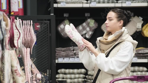 A young female customer chooses household goods while shopping in the kitchen section of a large hypermarket with a large assortment in a home goods store. photo