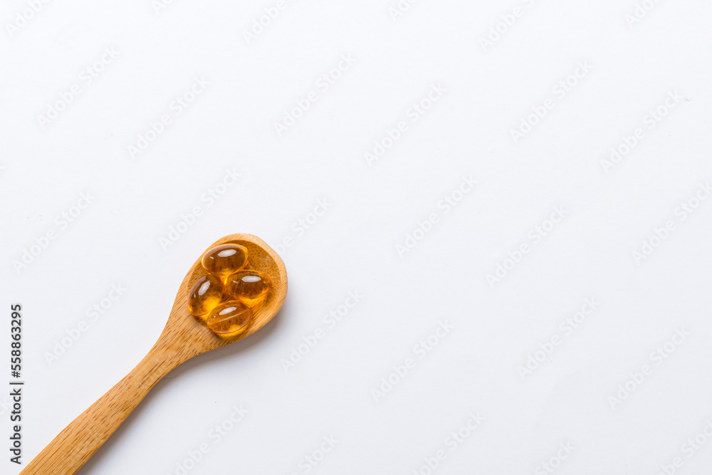 Vitamin omega capsules in a spoon on a colored background. Pills served as a healthy meal. Red soft gel vitamin supplement capsules on spoon Vitamin omega capsules in a spoon on a colored background. Pills served as a healthy meal. Red soft gel vitamin supplement capsules on spoon