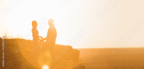 Silhouettes of man and woman in the mountains at sunset. Happy couple in love. 