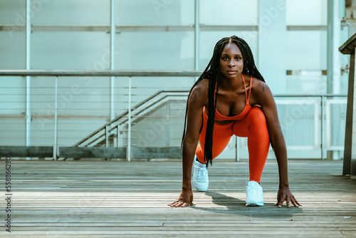 Fit black woman runner in crouch start ready to sprit in modern city