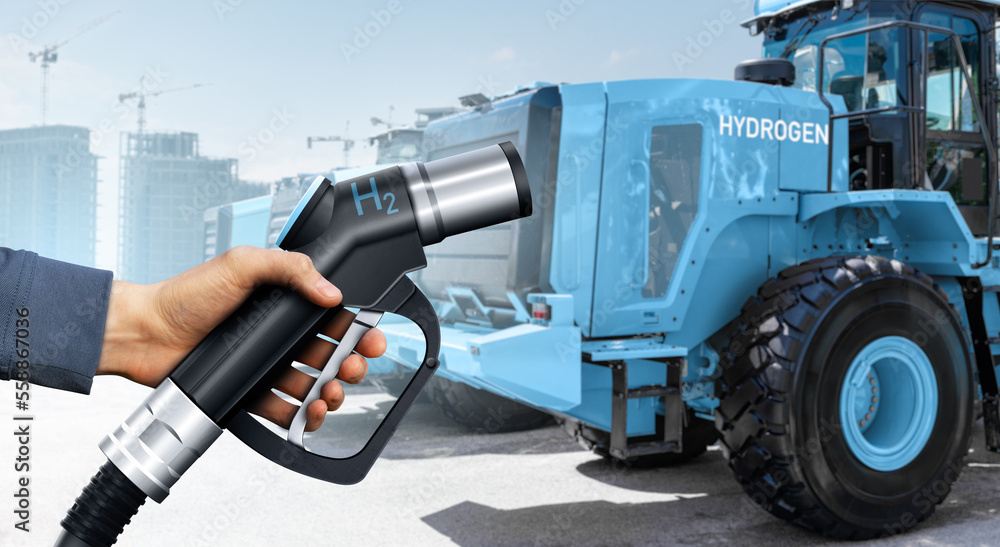 Hand with hydrogen fueling nozzle on a background of fuel cell construction machines. Concept Hand with hydrogen fueling nozzle on a background of fuel cell construction machines. Concept
