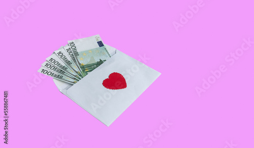 Paper envelope with 100 euro banknotes and a red heart on a pink background. With copy space to add text. Banknotes stick out from the envelope. Conceptual gift for Valentine's Day, wedding, birthday.
