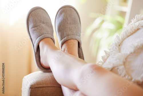 Legs, relax and woman in slippers on sofa resting on weekend at home. Shoes, freedom and female relaxing, lying and spending time alone on comfy, cozy and comfortable couch in living room of house. photo