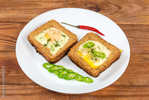 Two open sandwiches with fried egg on a white dish