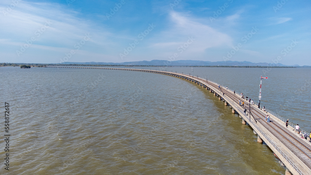 Obraz premium Aerial view of an amazing travel train parked on a floating railway bridge over the water of the lake in Pa Sak Jolasid dam with blue sky at Lopburi, Thailand.