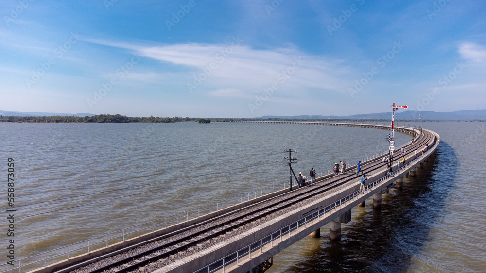 Obraz premium Aerial view of an amazing travel train parked on a floating railway bridge over the water of the lake in Pa Sak Jolasid dam with blue sky at Lopburi, Thailand.