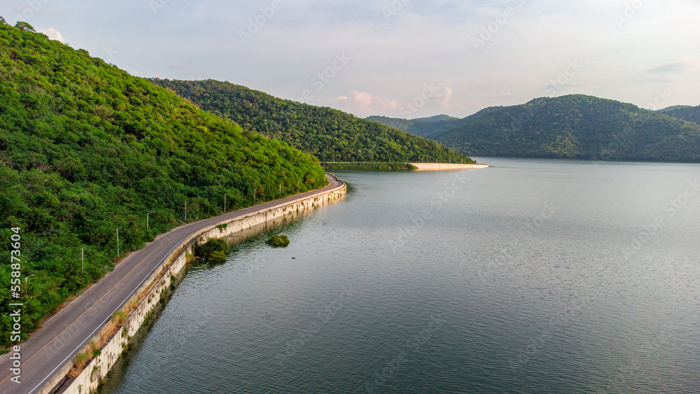 Muak Lek reservoir in Saraburi from aerial bird eye view. Beautiful unseen nature at Muak Lek dam with roadway beside with water and tree hill.