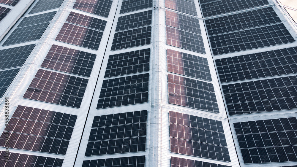 Fly over Solar cells on the roof of a large industrial factory. Solar roofs are generating renewable energy for the industry. The goal is to reduce the cost of electricity.